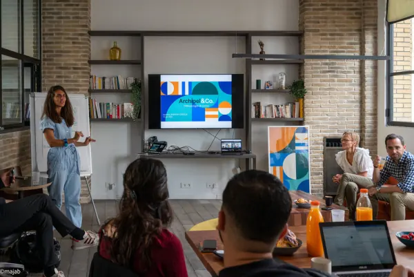 Le Loft en configuration atelier : présentation sur écran devant un petit groupe, murs de briques et verrière
